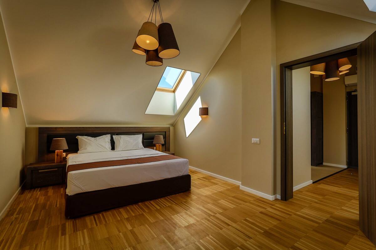 Ein Schlafzimmer mit einem großen Bett, einem Oberlicht und einem Holzboden.