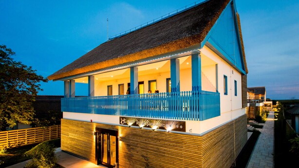 Un bâtiment à deux étages doté d’un balcon, d’un toit de chaume et d’une façade en bois.
