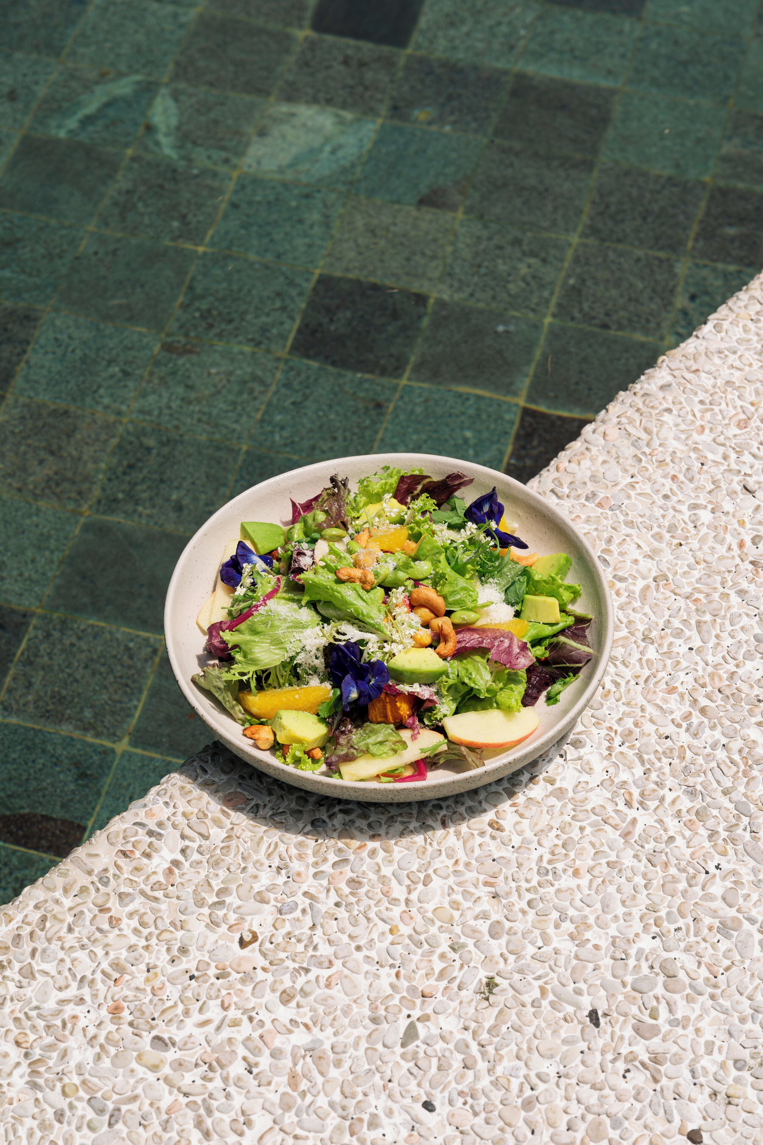 A bowl of salad on a textured surface.