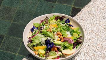 A bowl of salad on a textured surface.