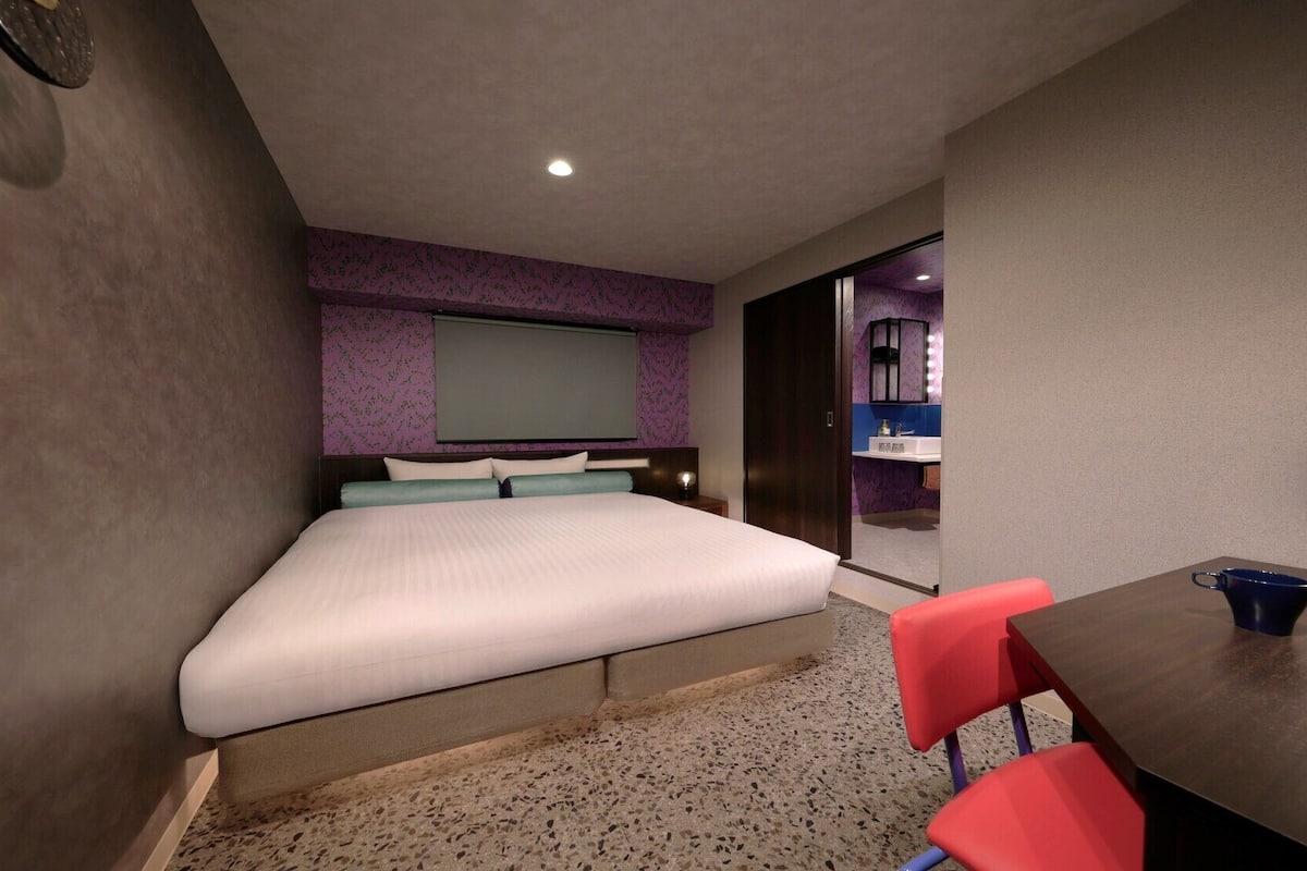 A hotel room with a bed, a desk, and a chair.