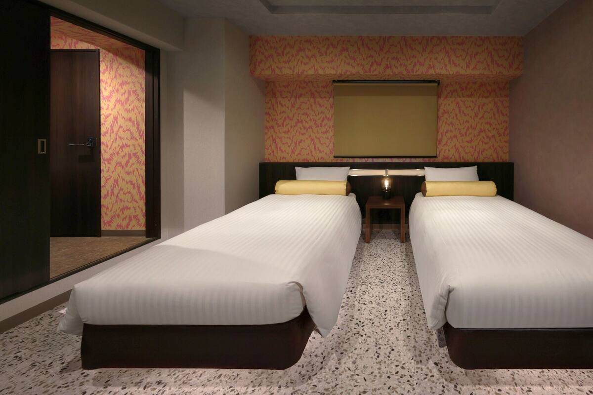 A hotel room with two beds, a large mirror, and a carpeted floor.