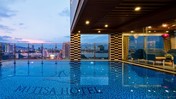 A rooftop infinity pool with a city view, checkered pillars, and modern lounge seating. - Mitisa Hotel Da Nang - Near Dragon Bridge (Da Nang)