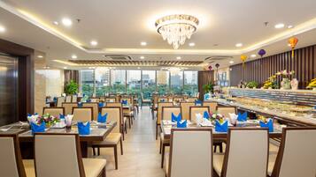 A restaurant with multiple dining tables, chairs, and a buffet area.