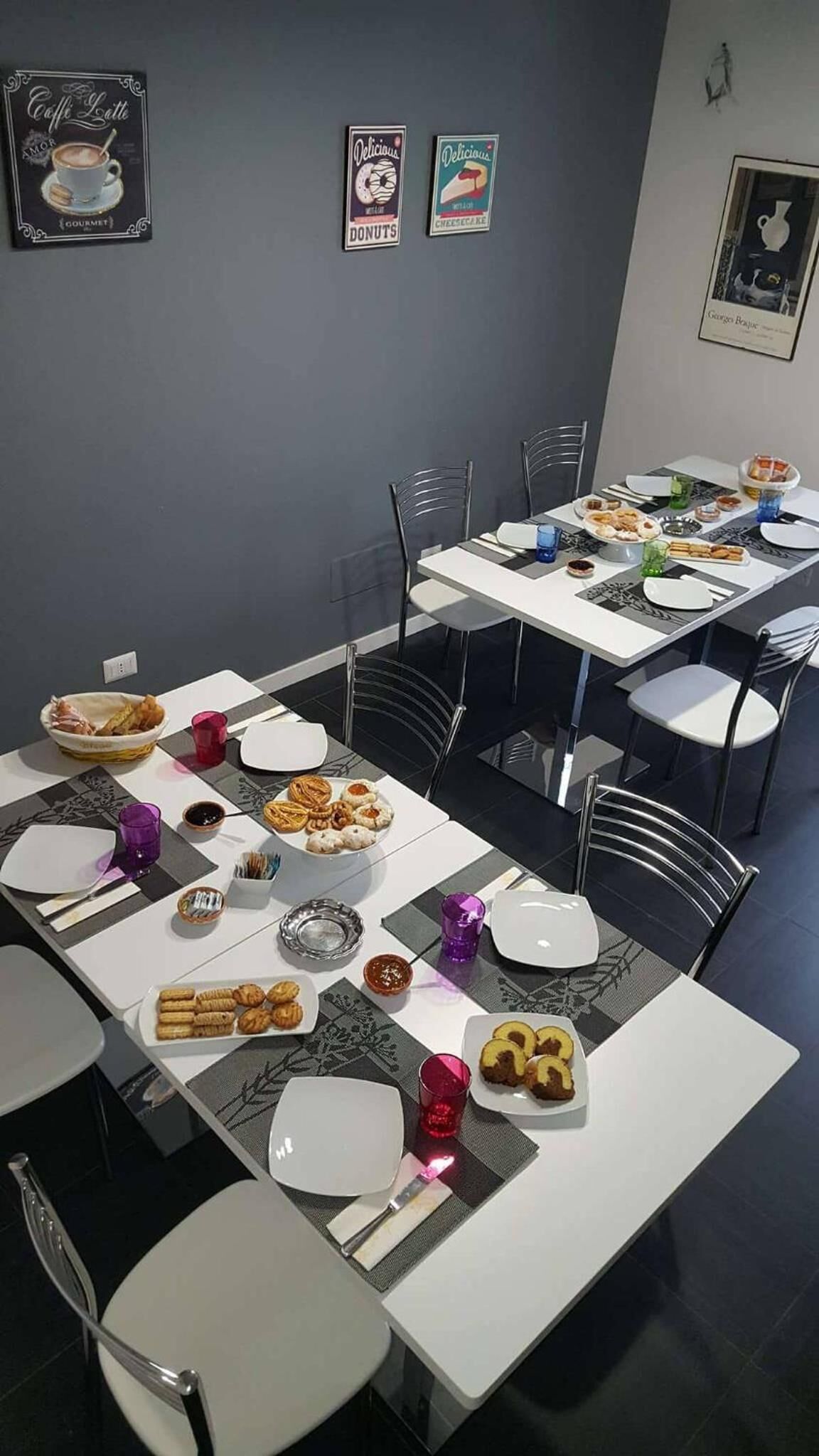 A dining area with tables set for a meal, featuring plates of pastries and a variety of dishes.