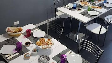 A dining area with tables set for a meal, featuring plates of pastries and a variety of dishes.
