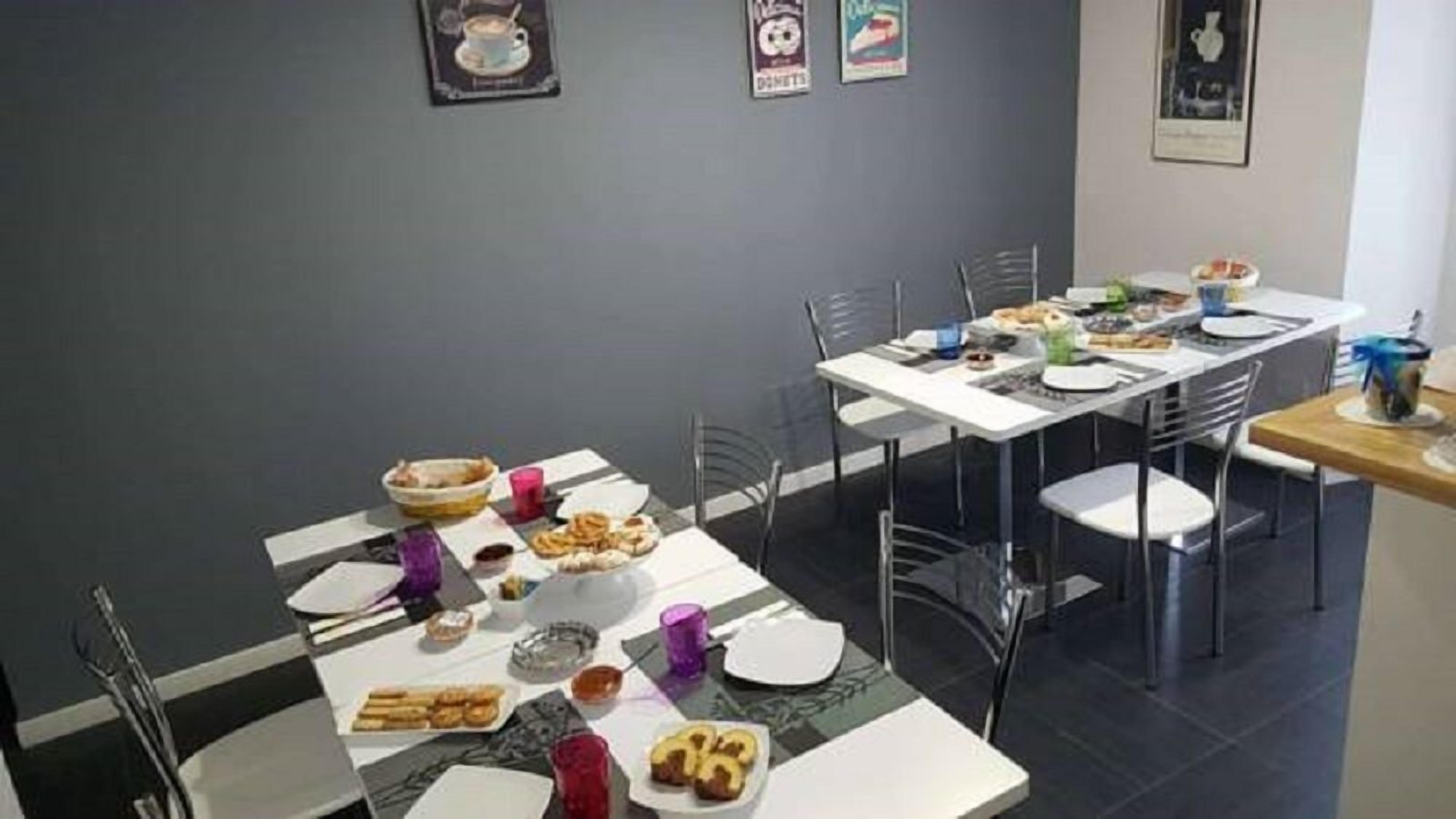 Un comedor con varias mesas y sillas, distintos platos y bebidas sobre las mesas, y adornos en las paredes.