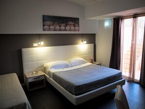 A hotel room with a large bed, bedside tables, a nightstand, a wall-mounted painting, and a window with curtains. - B&B Villa Letizia Inn (Castelbuono)