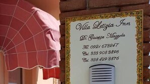 Placa indicativa do Villa Letizia Inn, com informações de contacto e um ícone de telefone.