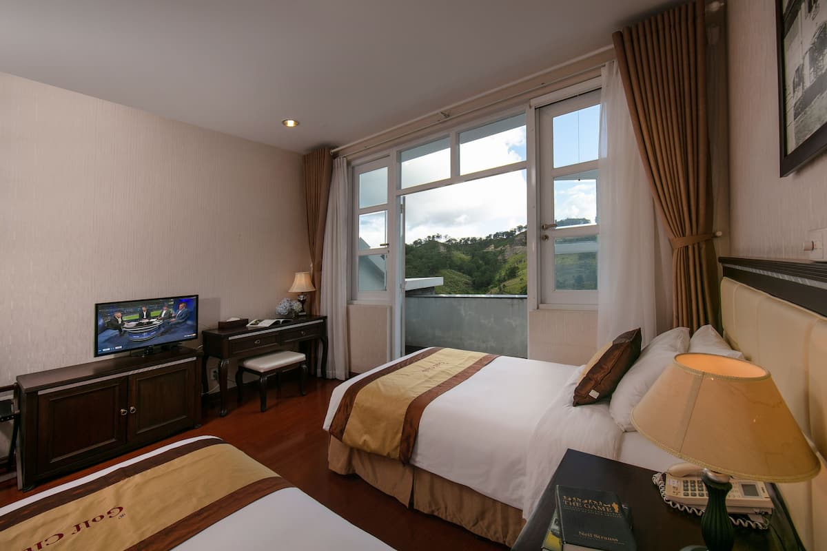 Une chambre d’hôtel équipée d’un lit, d’un bureau avec un ordinateur, d’une chaise, d’une lampe et d’un téléviseur.