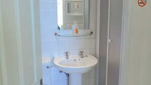 A bathroom with a white sink, toilet, and shower area. - Somerset House (Grange-over-Sands)