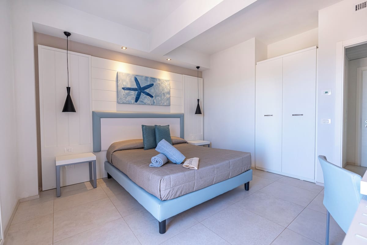 A modern bedroom with a bed, bedside tables, a wall-mounted artwork, and a wardrobe.