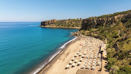 On the beach, black sand, sun loungers, beach umbrellas
