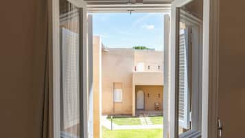 An open window with a view of a courtyard and a building outside.