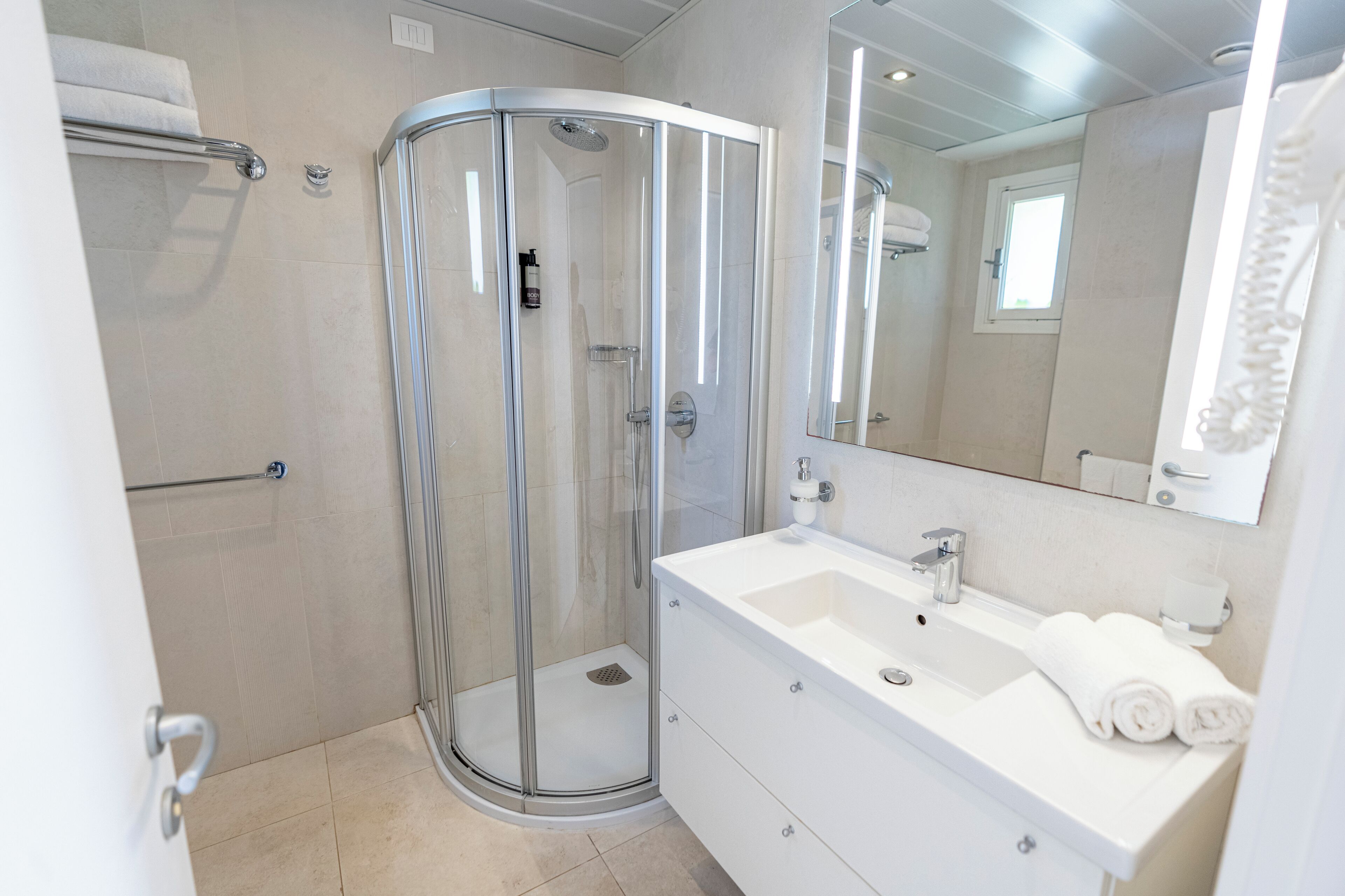 A modern bathroom with a glass-enclosed shower, a white sink, and a large mirror.
