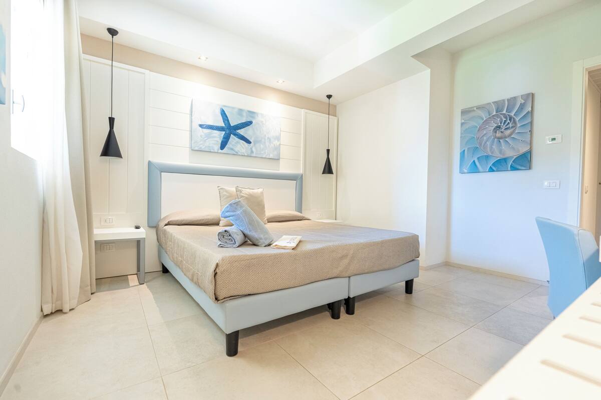 A bedroom with a bed, bedside tables, and artwork on the walls.