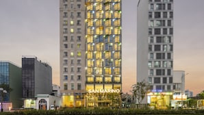 A modern hotel with a prominent 'SAN MARINO' sign, featuring a grid of illuminated windows and a central entrance. - San Marino Boutique Danang (Da Nang)