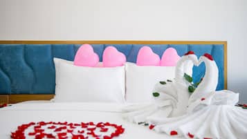 A hotel room with a blue headboard, white bedding, and decorative swans made of fabric.