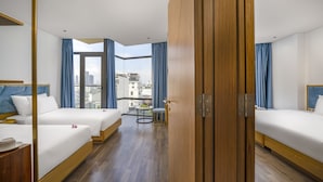 Une chambre d’hôtel avec deux lits, une petite table avec une chaise et une vue sur la ville grâce à de grandes fenêtres.