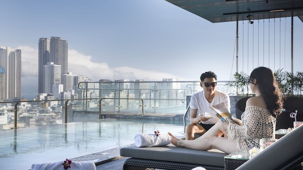 Un espace piscine sur le toit, offrant une vue sur la ville, avec des chaises longues et une barrière en verre.
