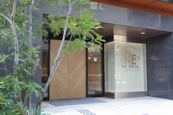 L'esterno dell'hotel RE, dal design moderno, con ingresso in vetro e cartello parcheggio ben visibile.