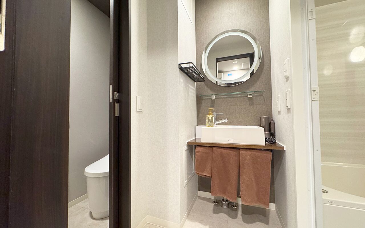 Een moderne badkamer met toilet, wastafel en spiegel.