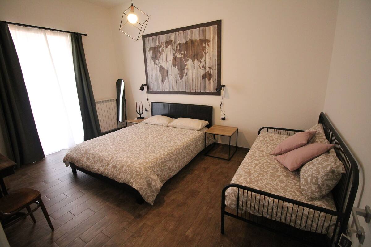 A bedroom with two beds, a desk, and a chair.