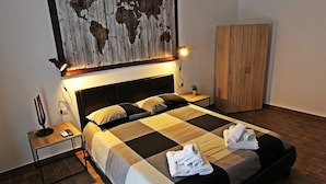 A neatly made bed with a checkered bedspread, a bedside lamp, a small table with a plant, and a wooden wardrobe. - Il Civico 2 (Bari)