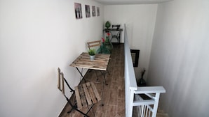 A narrow balcony with a wooden table, a chair, and a potted plant. - Il Civico 2 (Bari)