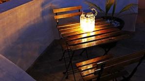 A wooden table with a glass jar lamp on it, placed on a patio with a potted plant nearby. - Il Civico 2 (Bari)