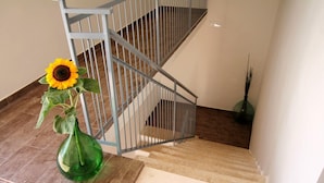 A staircase with a metal railing and a green vase with a sunflower on a tiled floor. - Il Civico 2 (Bari)
