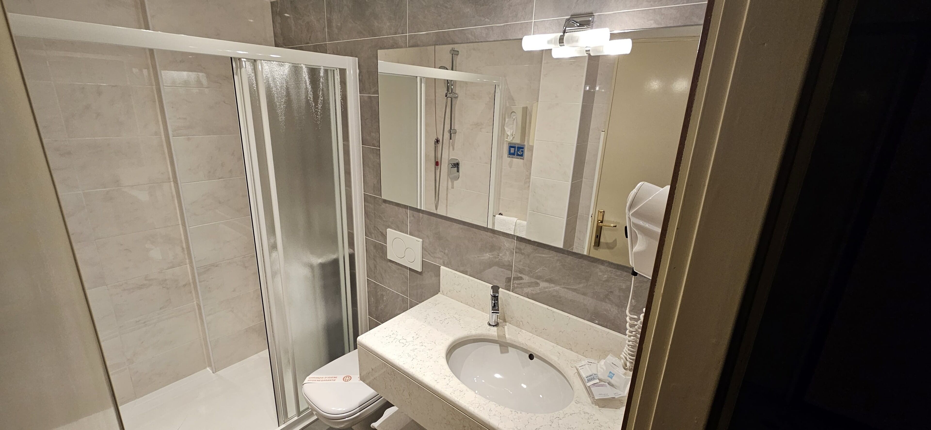 A modern bathroom with a glass-enclosed shower, a sink with a mirror above it, and a toilet.