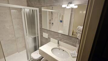 A modern bathroom with a glass-enclosed shower, a sink with a mirror above it, and a toilet.