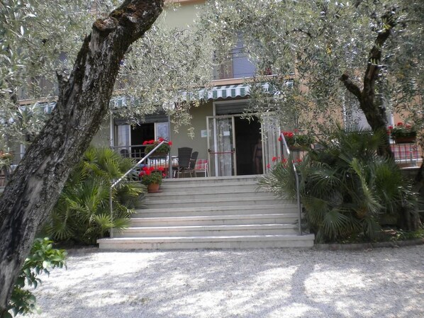 Un edificio con una escalera que conduce a una puerta, rodeado de árboles y plantas.