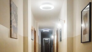 A hallway with wooden flooring, framed artwork on the walls, and recessed ceiling lighting. -  La Boheme SMART Hotel (Turin)