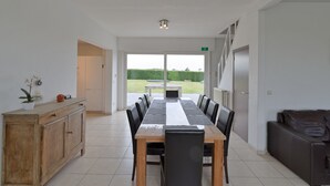 A dining area with a long table, chairs, a wooden cabinet, and a view of the outdoors. - Flanders Fields Cottage Leisele (Alveringem)
