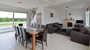 A spacious living area with a dining table, sofas, and a fireplace. - Flanders Fields Cottage Leisele (Alveringem)