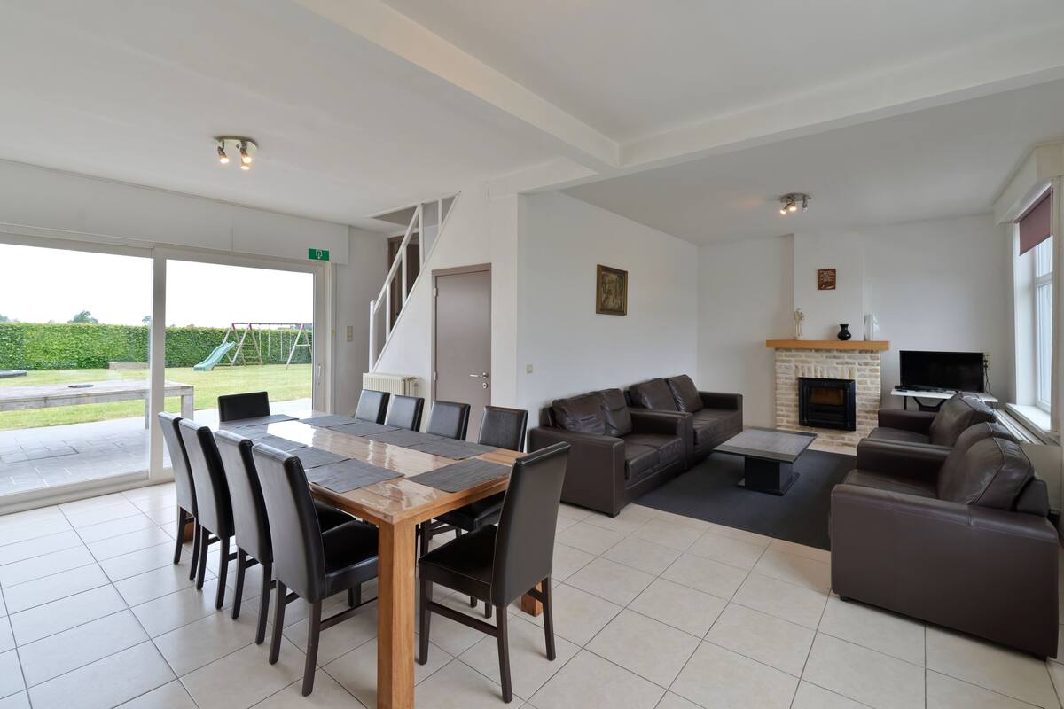 A spacious living area with a dining table, sofas, and a fireplace.