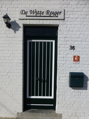 A white brick building with a black door, a sign reading "De Witte Reiger", and a mailbox. - Flanders Fields Cottage Leisele (Alveringem)