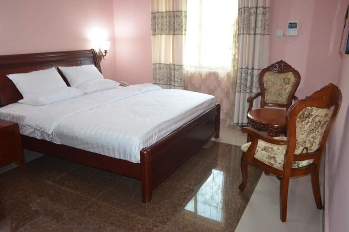 A bedroom with a wooden bed, a nightstand, a chair, and a small table.