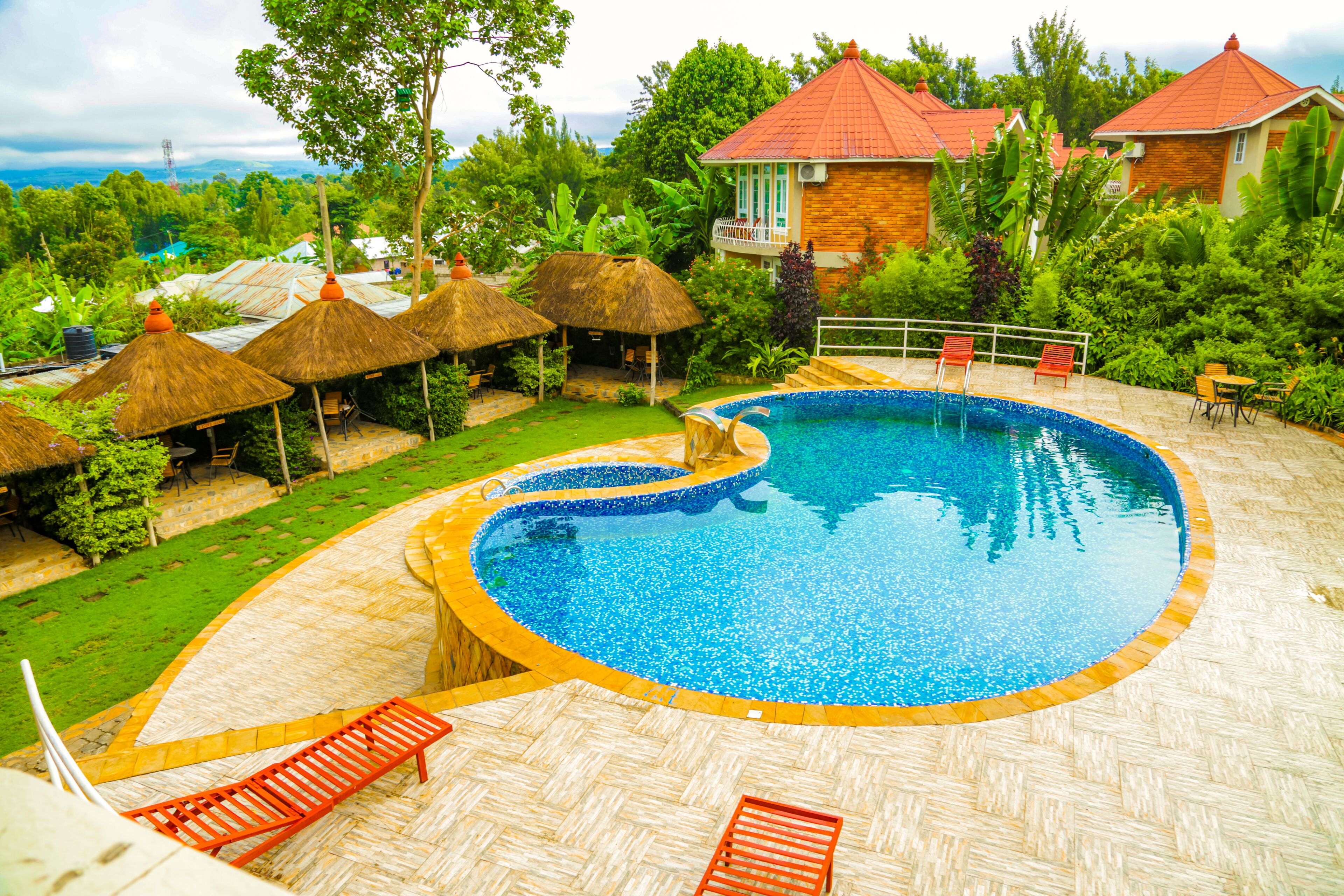 A swimming pool with a curved edge, surrounded by lounge chairs and thatched umbrellas.