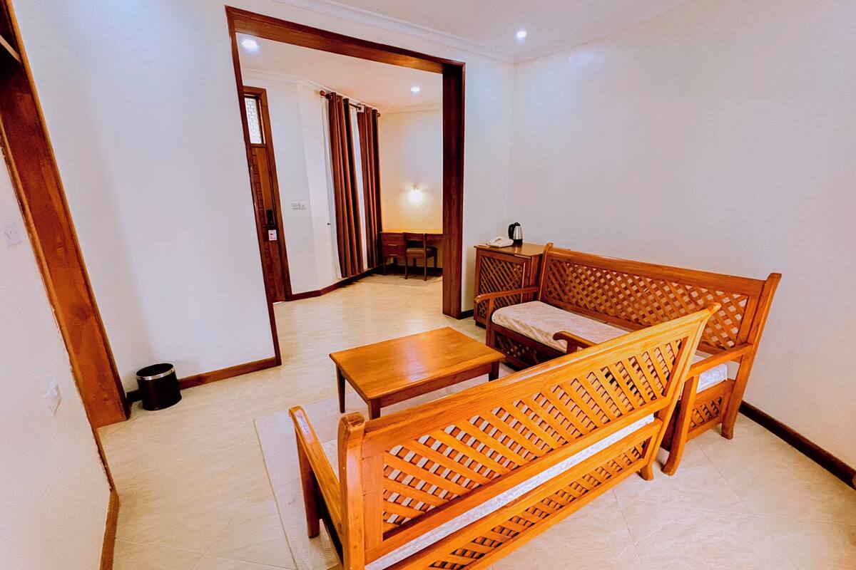 Una habitación con un sofá de madera, una mesita pequeña y un escritorio con una silla.