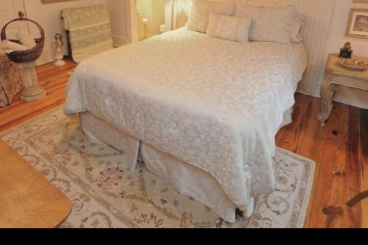 A bedroom with a large bed, a nightstand, a lamp, and a framed picture on the wall.