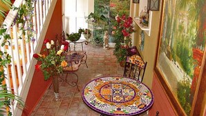 A hallway with a tiled floor, a round table with a colorful mosaic, and a staircase with a white railing. - Frog Hollow Bed and Breakfast (Lexington)