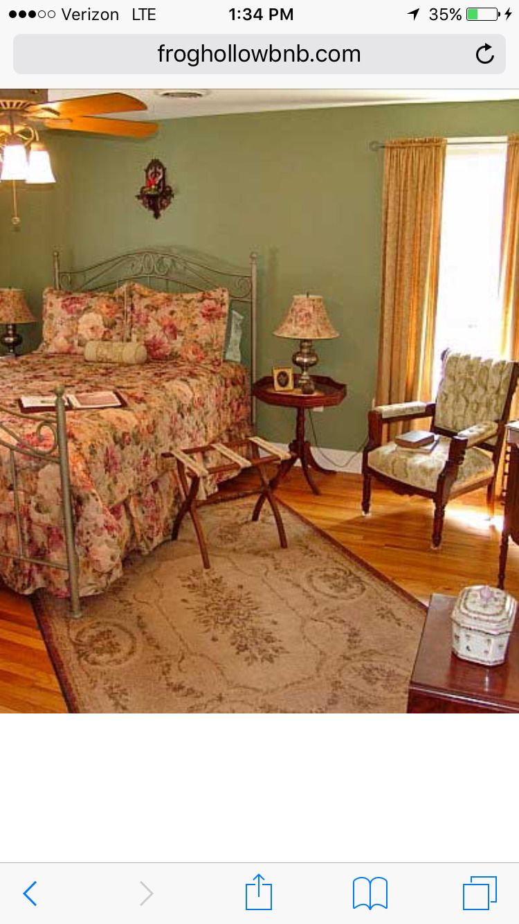 A bedroom with a bed, a chair, a small table, and a lamp.