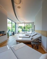Interior moderno com teto curvo, lareira e área de estar com poltronas confortáveis.