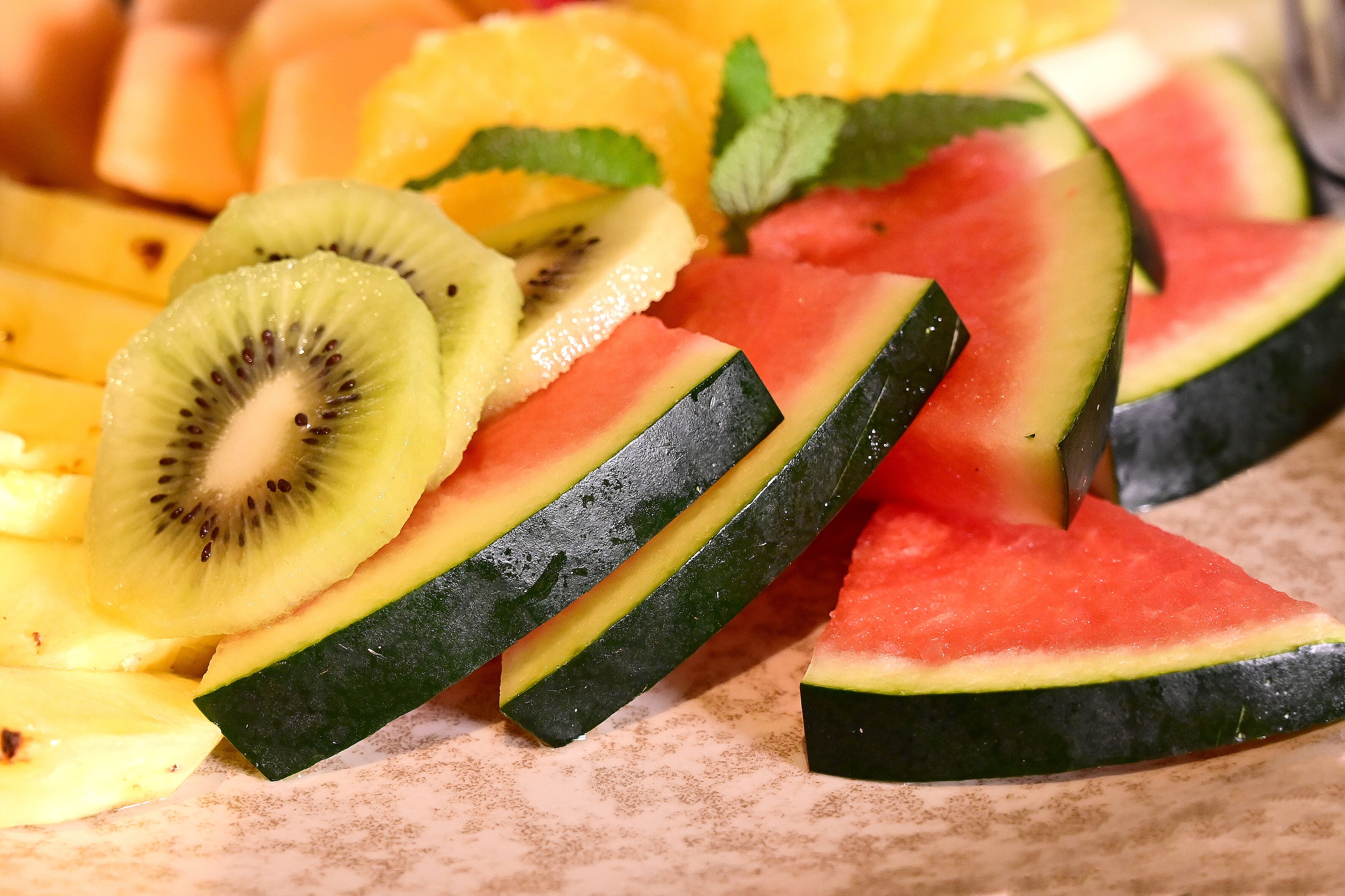 En närbild på uppskurna frukter, inklusive vattenmelon, kiwi och ananas.