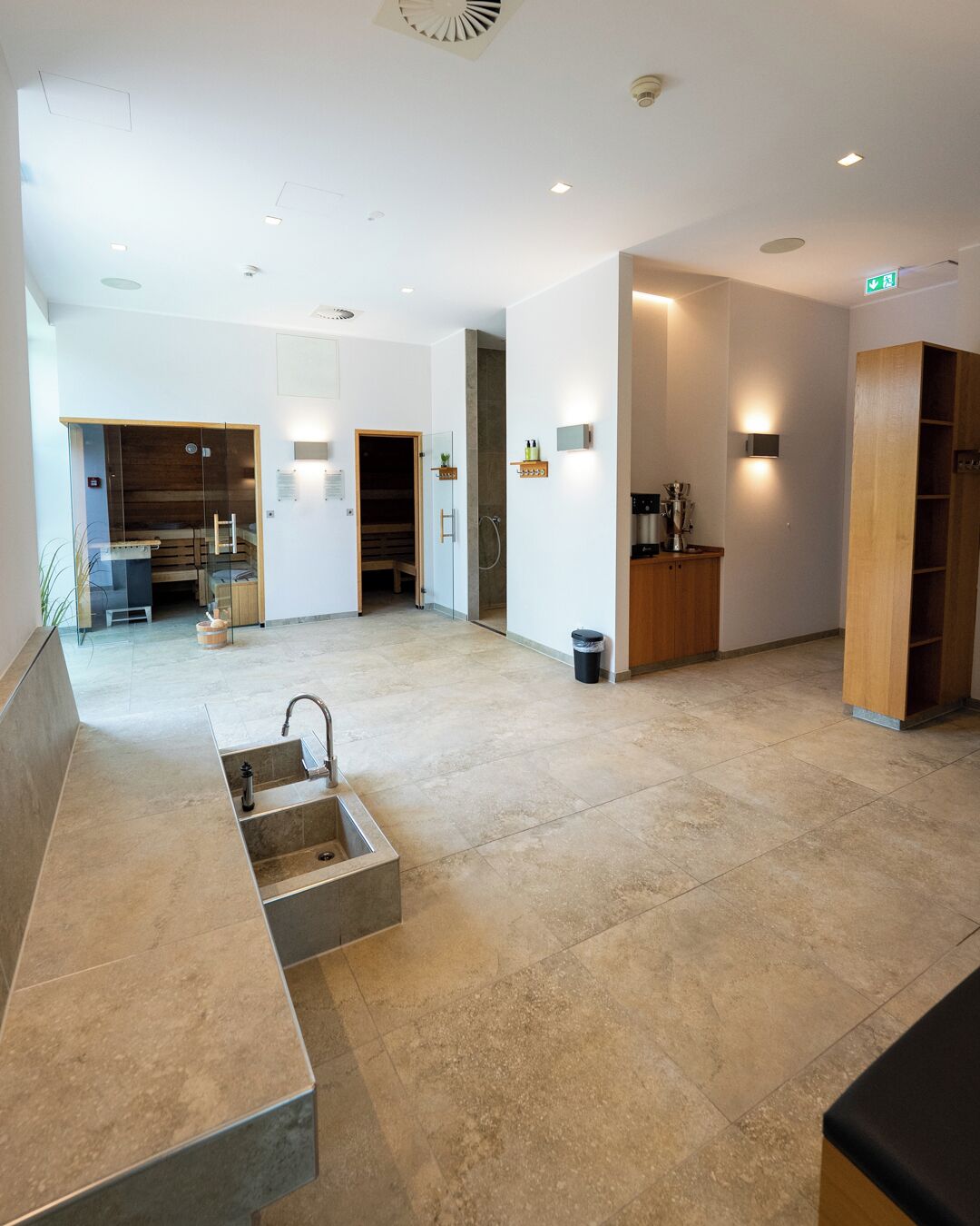 A spacious lobby with a reception desk, a seating area, and a sauna room.
