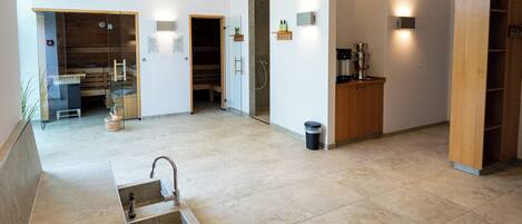 A spacious lobby with a reception desk, a seating area, and a sauna room.