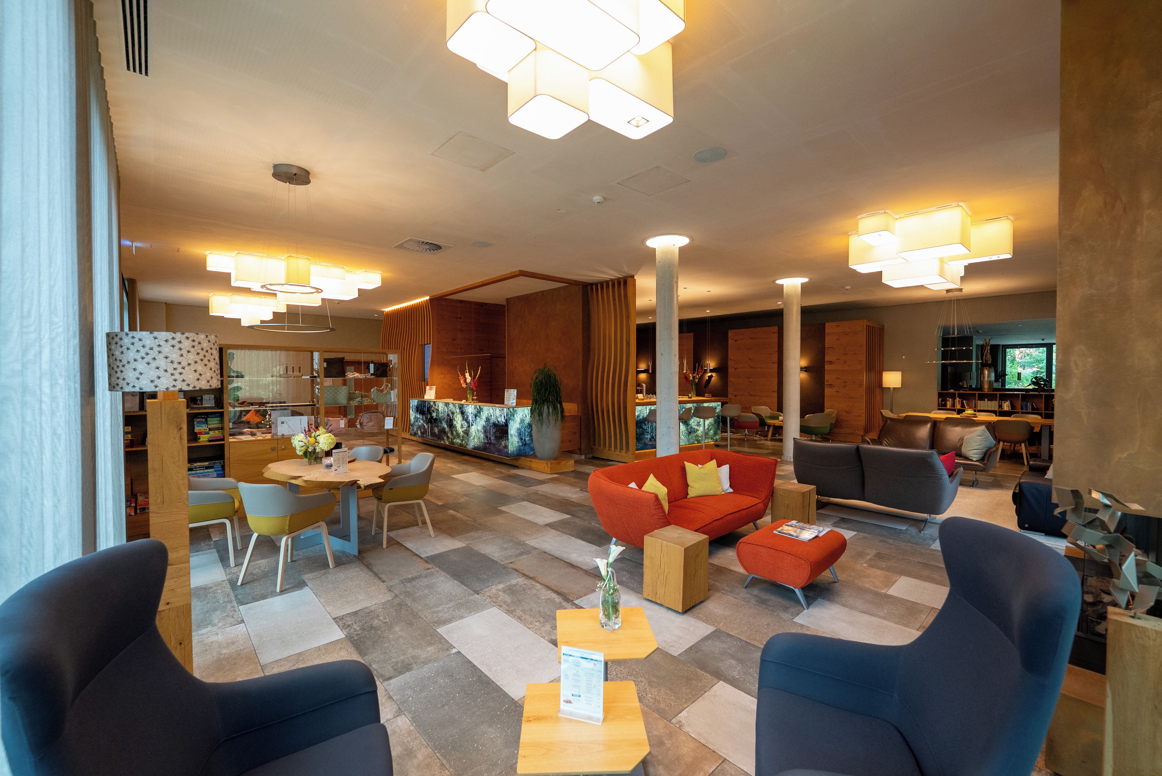 Un moderno vestíbulo de hotel con mostrador de recepción, zona de estar y bar.